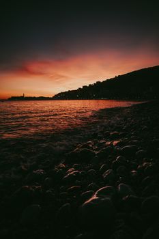 Captivating sunset over the rocky shore of Budva, Montenegro with a silhouette skyline.