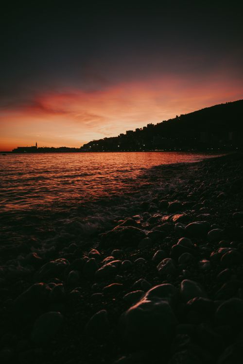 Free Captivating sunset over the rocky shore of Budva, Montenegro with a silhouette skyline. Stock Photo