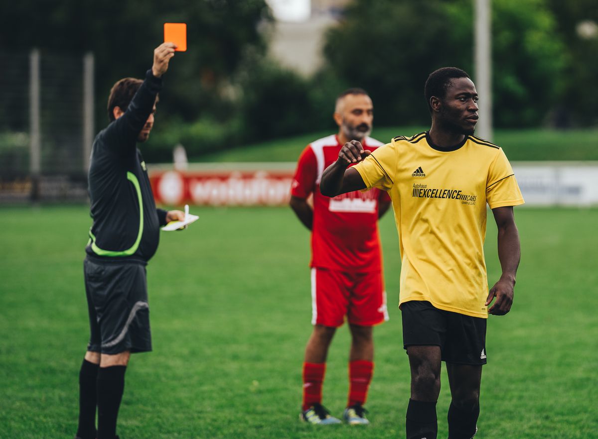 Árbitro mostrando una tarjeta roja a un jugador de fútbol