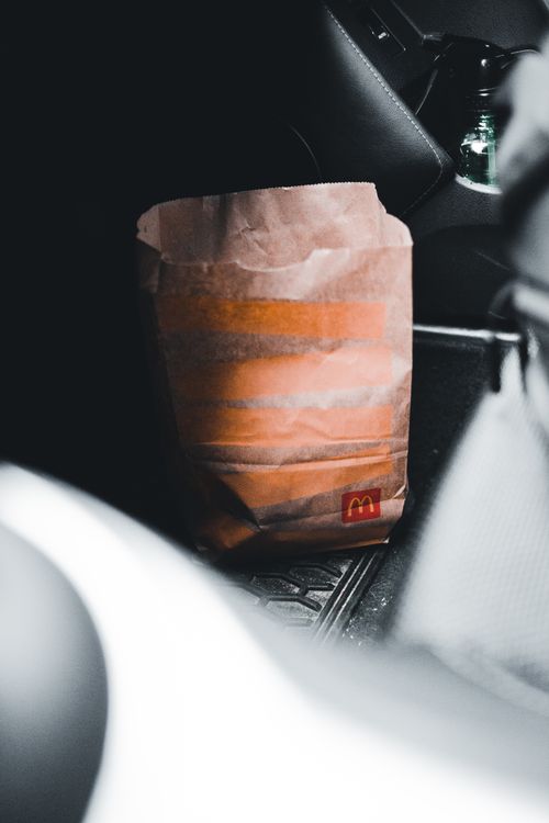 Free Close-up of a McDonald's paper bag inside a car, showcasing fast food takeaway experience. Stock Photo