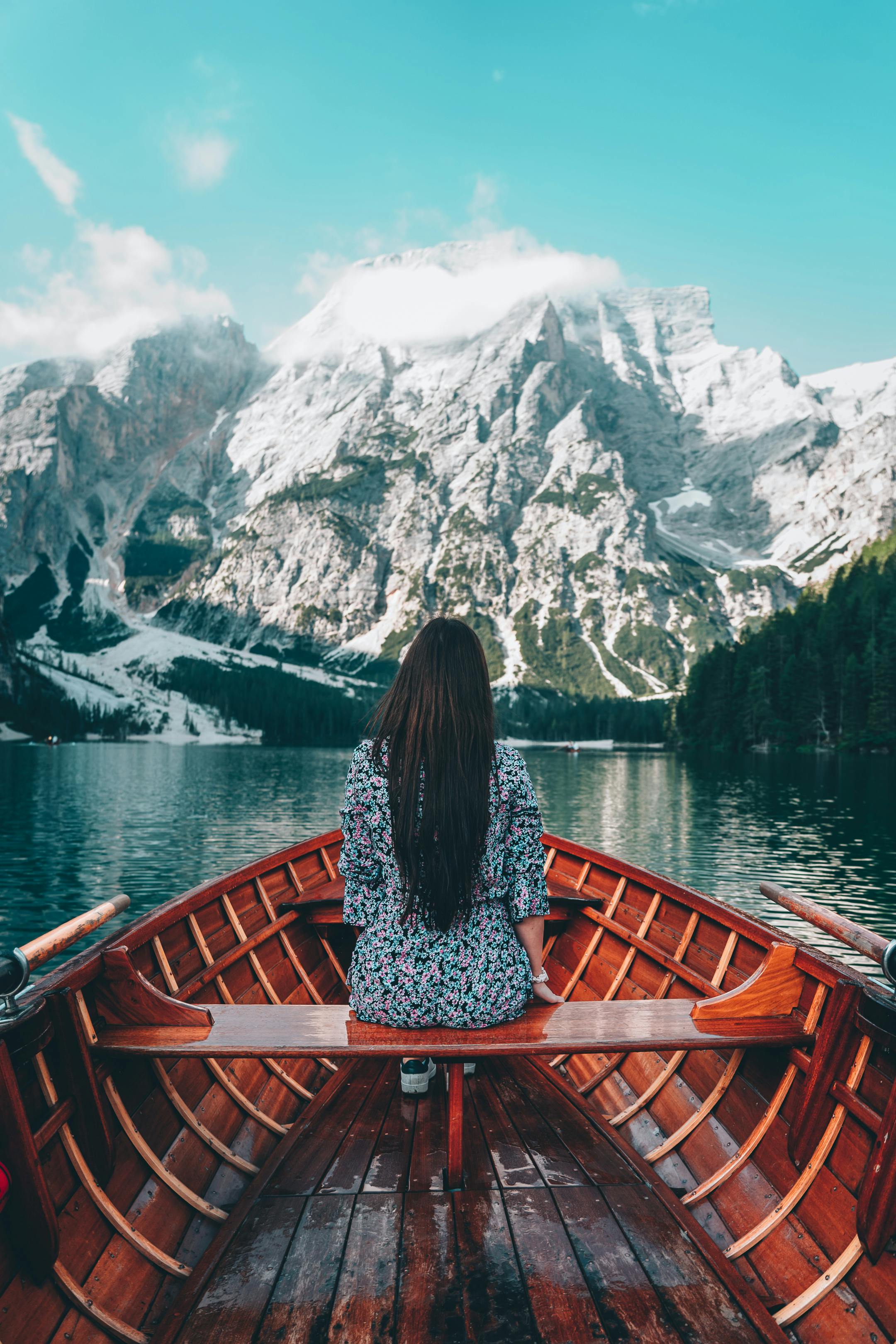 back view of woman in floral dress sitting on wooden boat