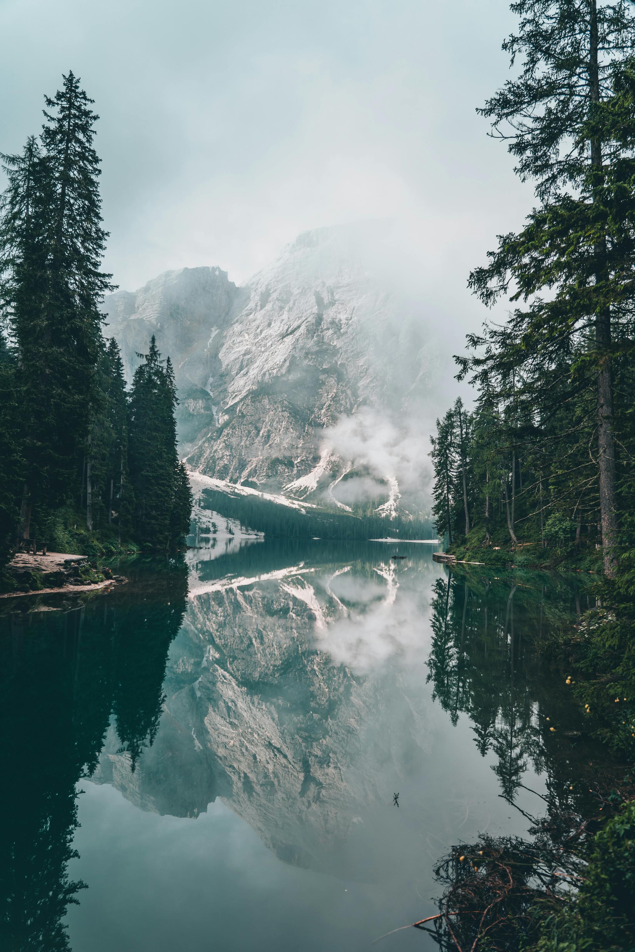 A tranquil mountain lake with mist and reflections creates a serene natural scene.