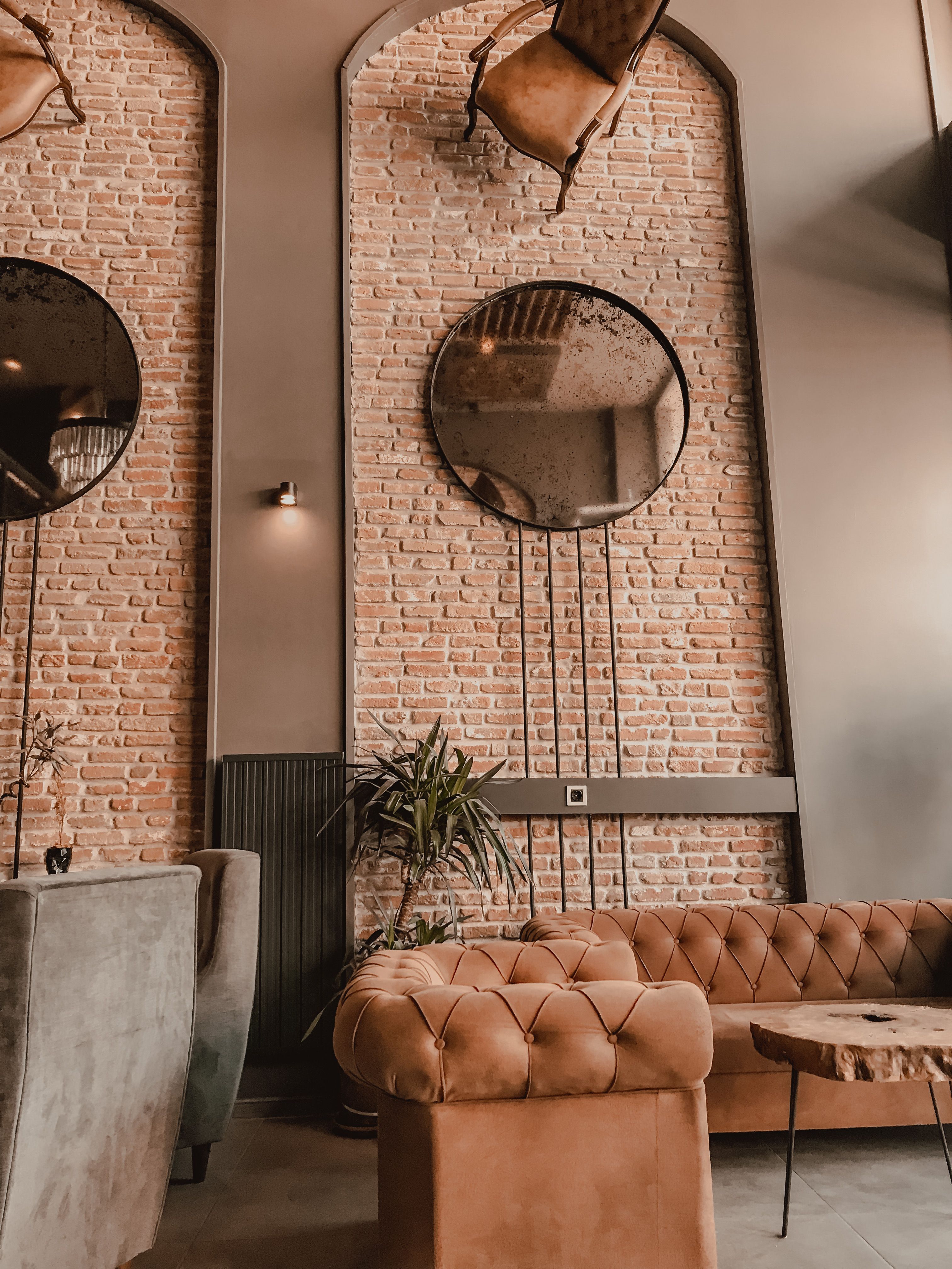 Salon avec mur de brique apparente, canapés et miroirs dans un appartement de style loft