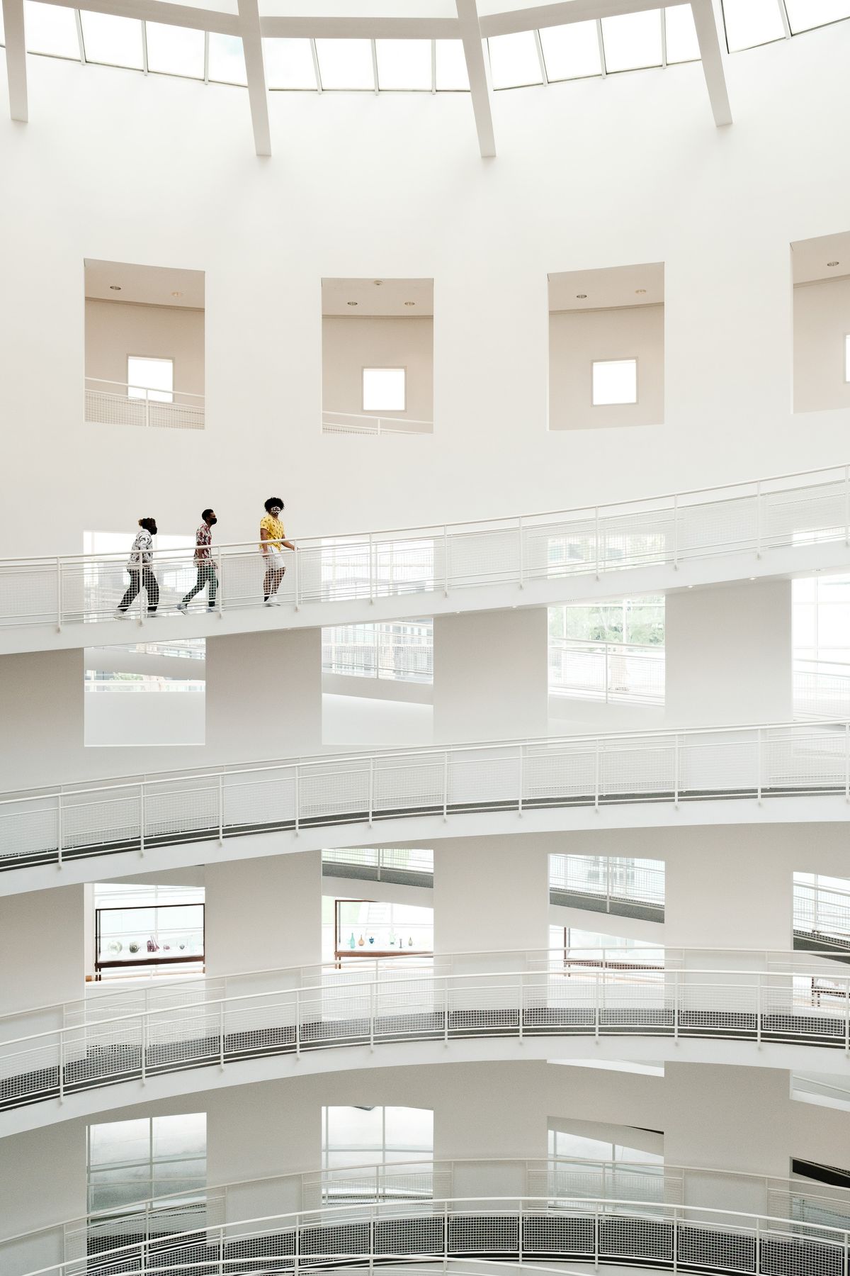 Visitors moving through a bright art museum with white walls