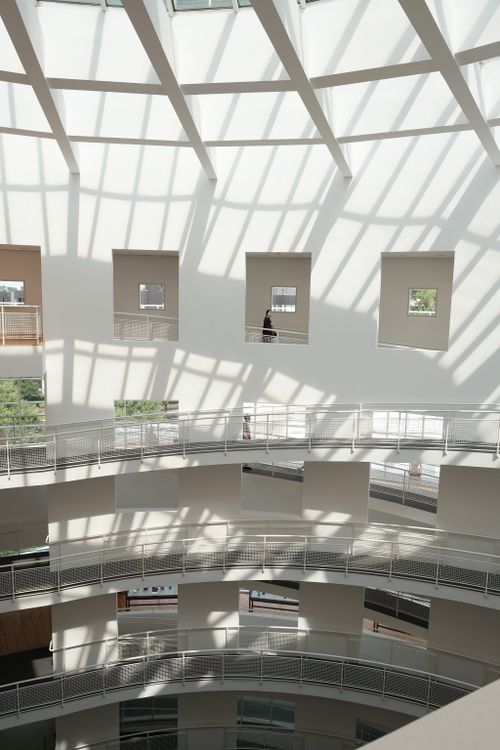 Free Interior view of a modern building with a spiral staircase and sunlit shadows. Stock Photo