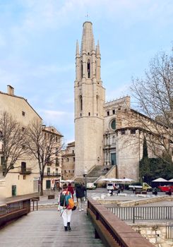 View of the Church of St. Felix and footbridge in Girona, Spain with people walking.