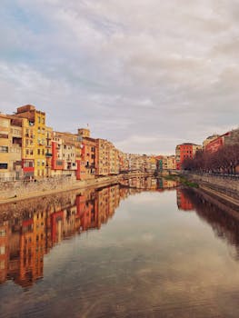 Vibrant buildings reflected in the calm Onyar River in Girona, Spain during daytime.