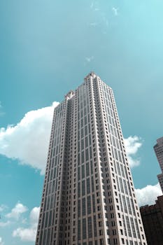 Vertical high-rise building with modern architecture set against a bright blue sky and white clouds.