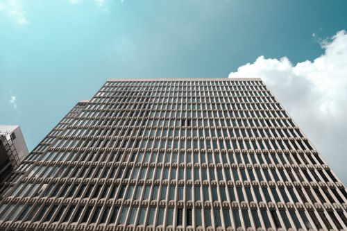 Free Low-angle view of a contemporary high-rise building with unique architectural design against a cloudy blue sky. Stock Photo