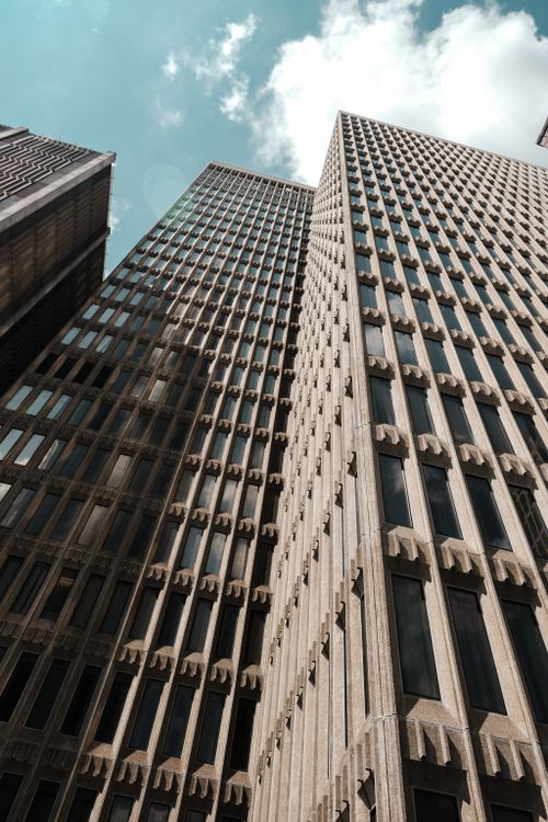 Free Dramatic view of high-rise urban buildings against a cloudy blue sky, reflecting modern architecture. Stock Photo