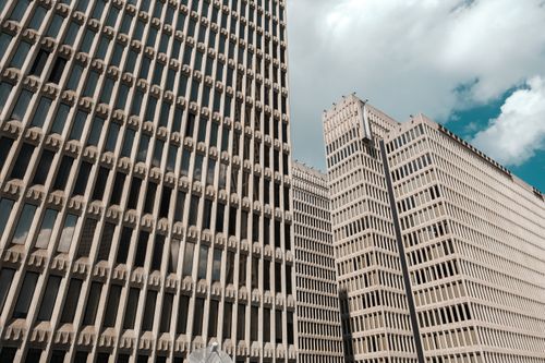 Free Perspective shot of distinctive high-rise office buildings with patterned facades under a blue sky. Stock Photo