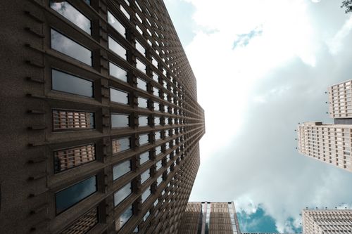 Free Dramatic low-angle skyscraper view with reflective windows and clouds above. Stock Photo