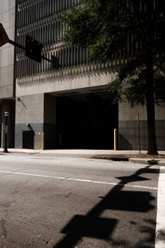 A city street with shadows from trees and traffic lights cast on the pavement.