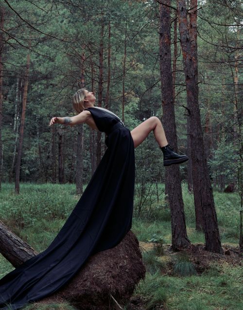 Free Artistic photo of a stylish woman in a black dress, floating in a mystical forest setting. Stock Photo