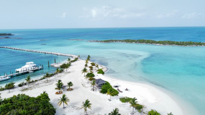 A white-sand island with palms, a dock and turquoise shallows