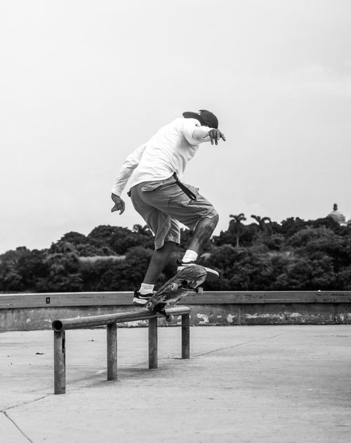 Free Dynamic black-and-white photo capturing a skateboarder performing a trick on a rail. Stock Photo