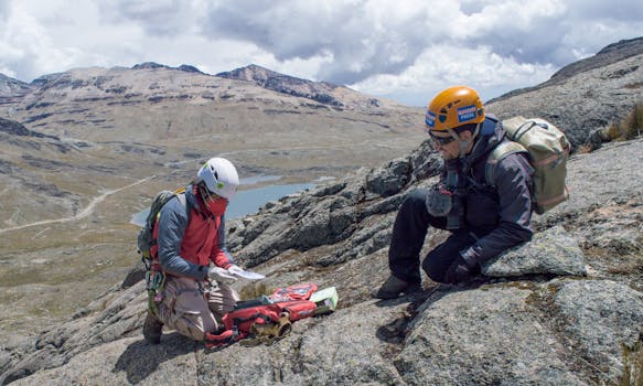Two climbers navigate the rugged mountainous terrain using maps and equipment.