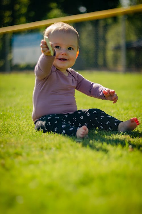 Free Close-Up Shot of a Cute Baby Sitting on the Grass Stock Photo