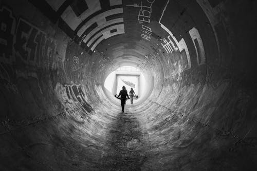 Silhouette of Person Walking on Tunnel