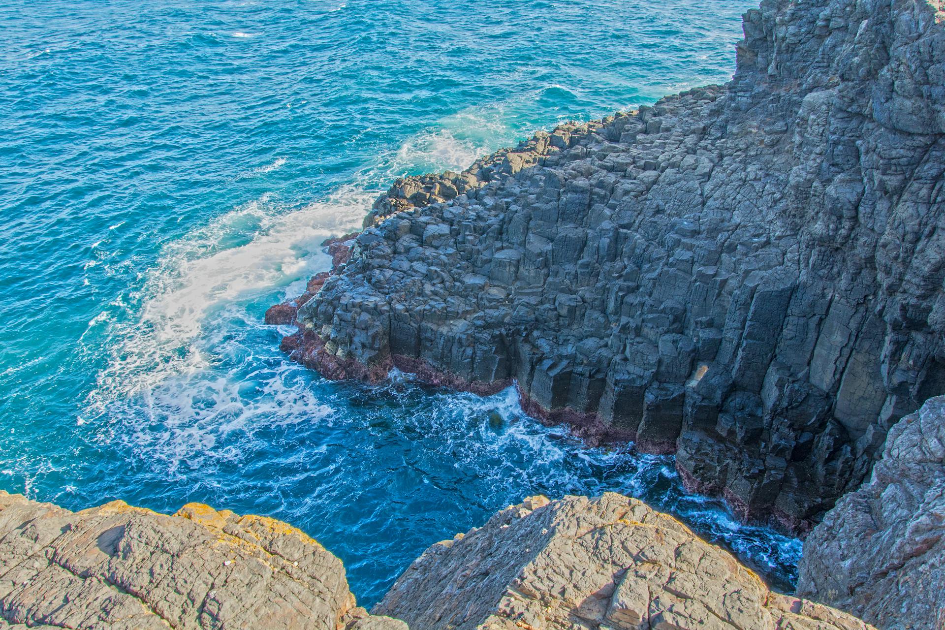 Scenic view of the dramatic coastal cliffs in Kiama, Australia, featuring turquoise water and rugged rock formations.