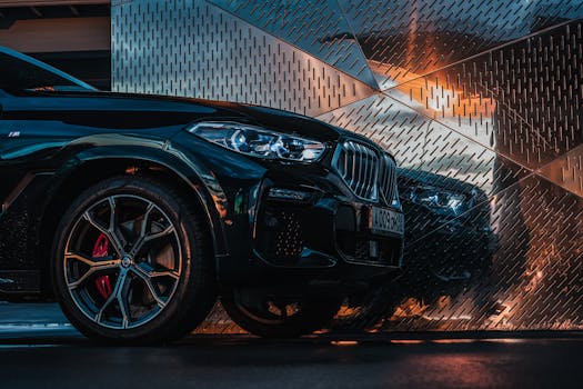 A stylish black luxury car parked with striking reflections and glowing headlights in a modern setting.
