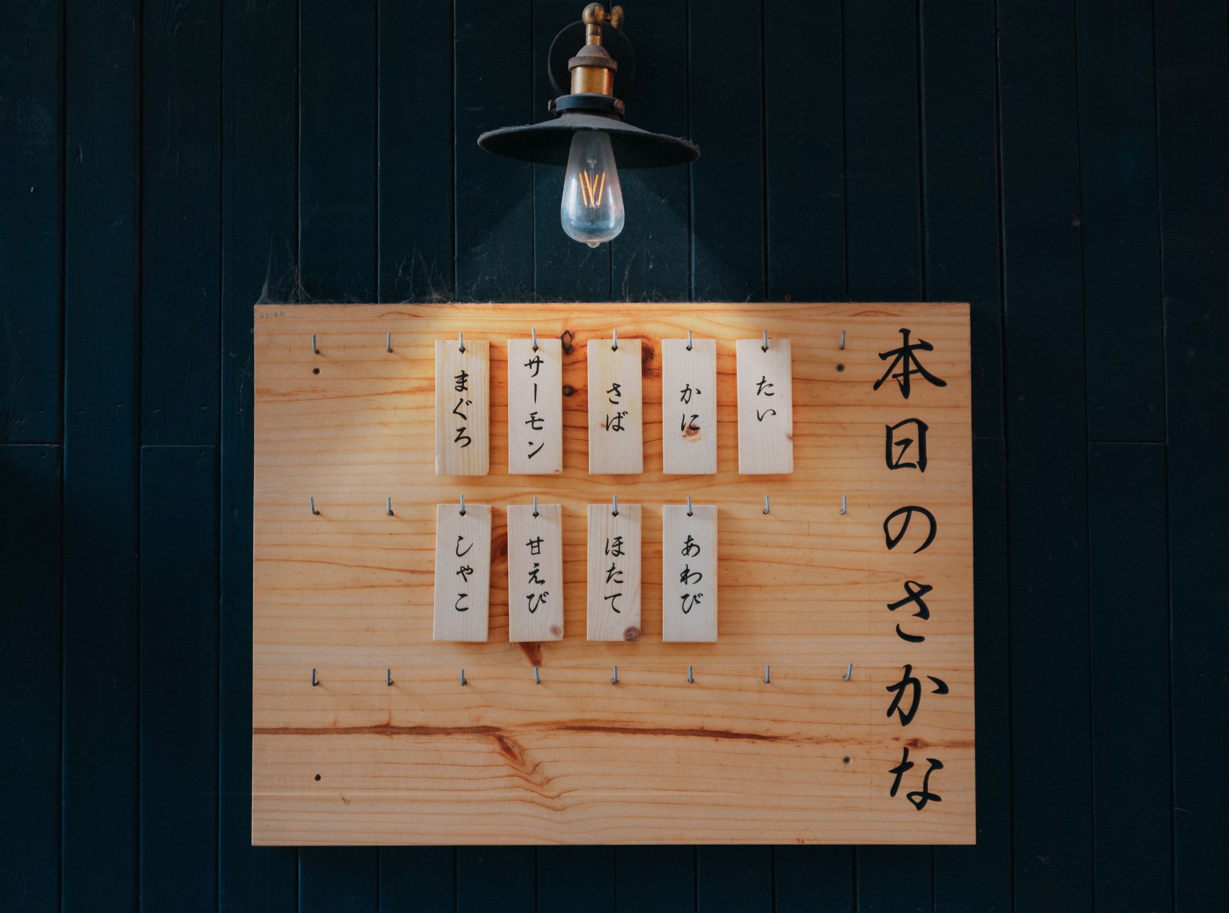Vintage wooden menu board lit by a hanging bulb
