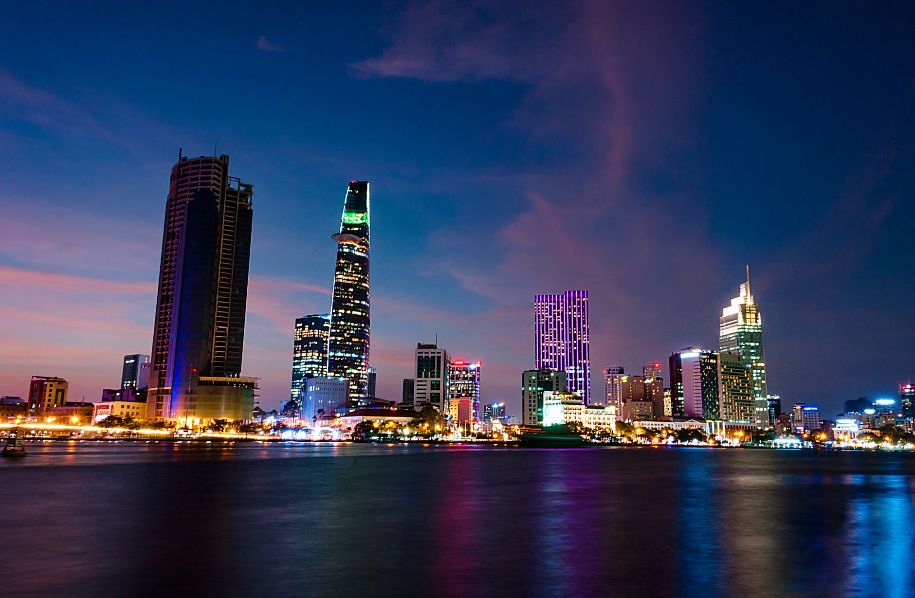 A stunning evening view of Ho Chi Minh City's skyline reflecting vibrant lights over the Saigon River.