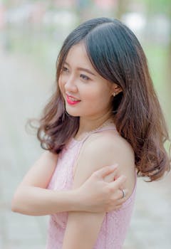 一位优雅的女人穿着粉色衣服微笑，捕捉到户外柔和梦幻的氛围