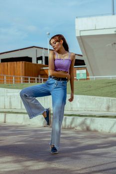 Fashionable woman striking a pose outdoors with modern architecture in the background.