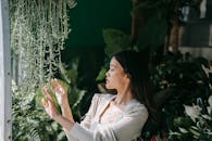 Woman in White Long Sleeve Shirt Holding Green Plant