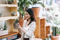 Woman in White Long Sleeve Shirt Holding Green Plant