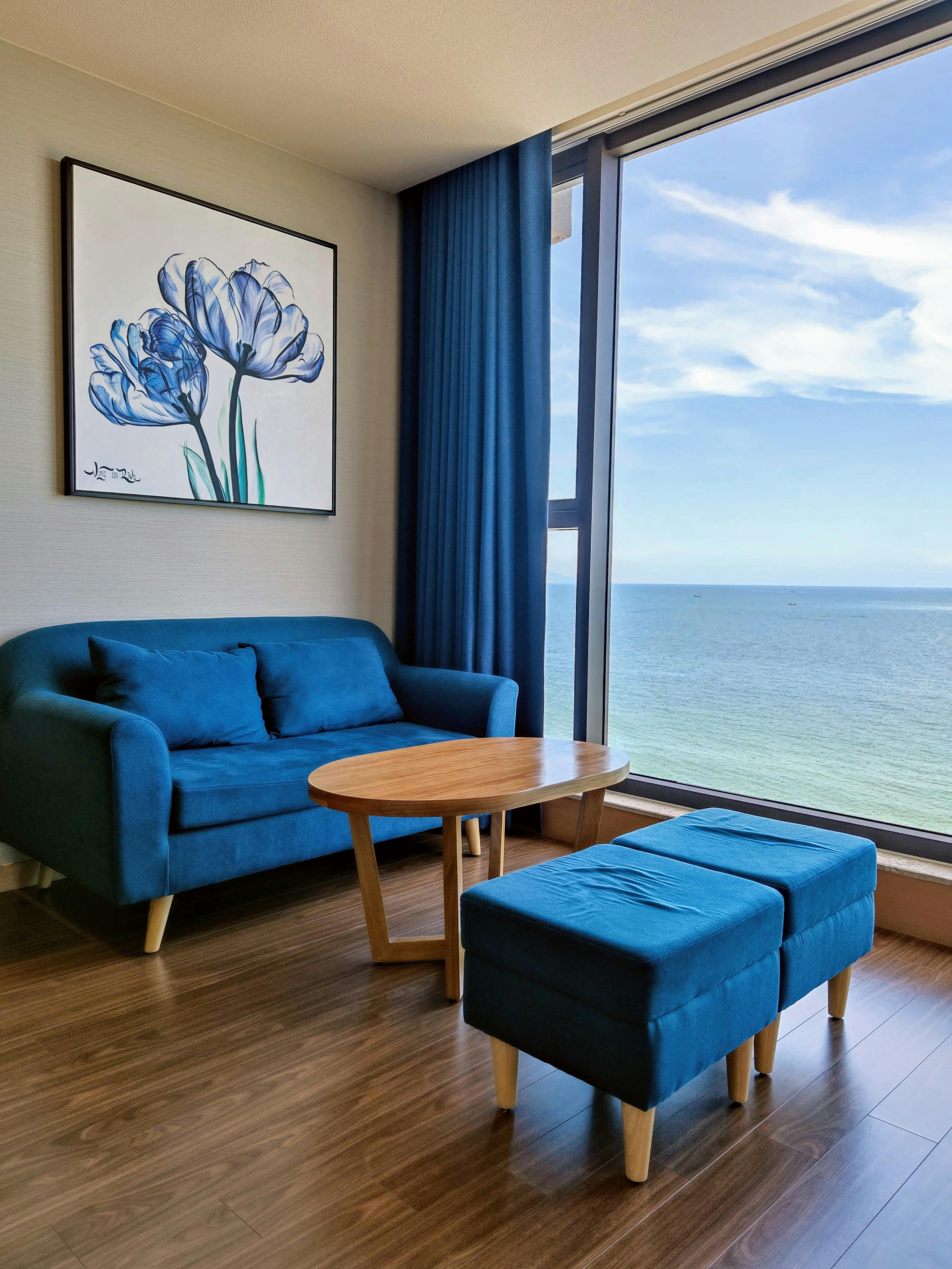 Bright interior with ocean view from Vũng Tàu apartment, blue sofa and modern art.
