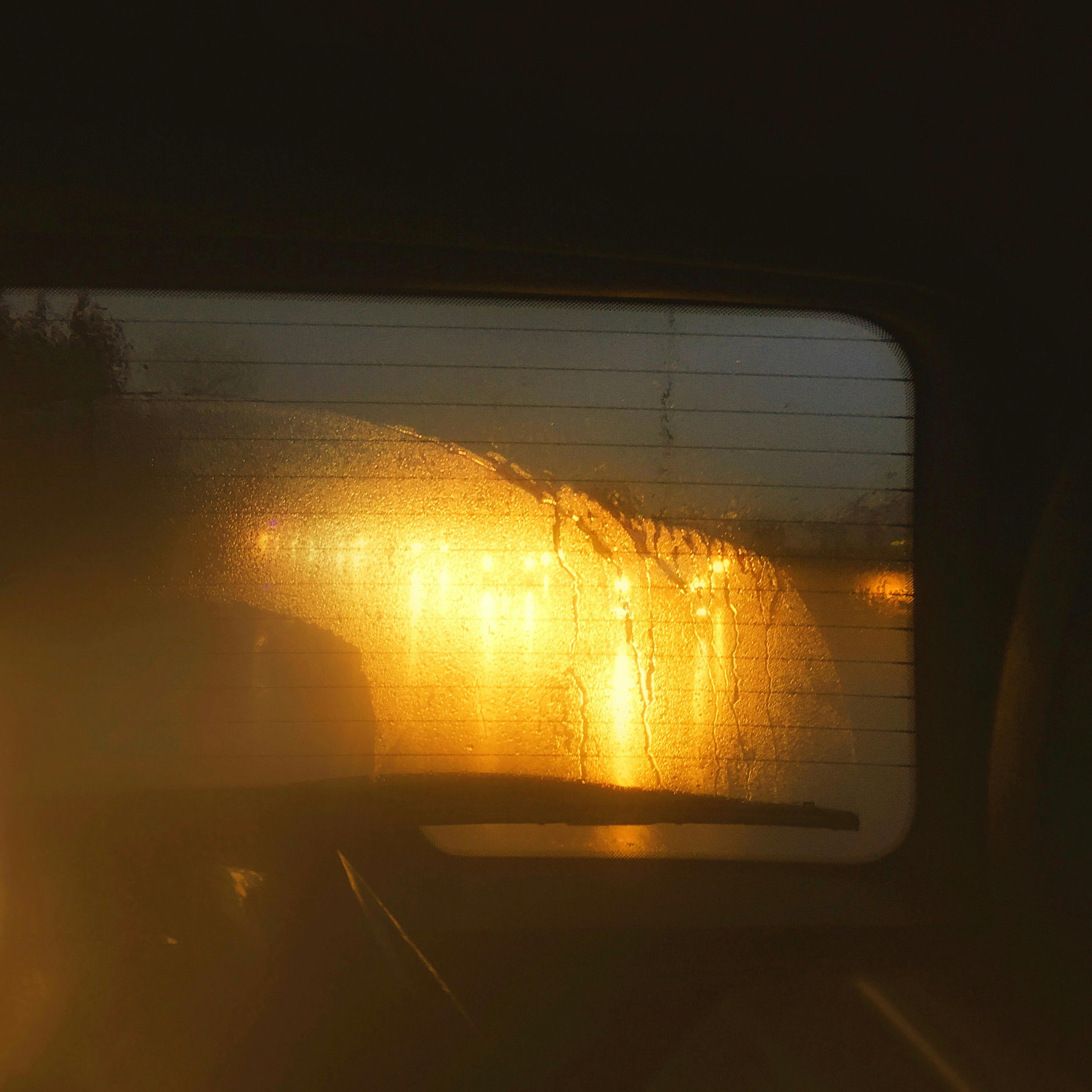 Moody nighttime view through a wet car window with blurred city lights in Pendik, İstanbul.