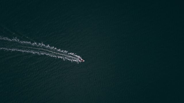 A lone boat cutting a wake across dark ocean water — photo by Jess Ruyter on Pexels