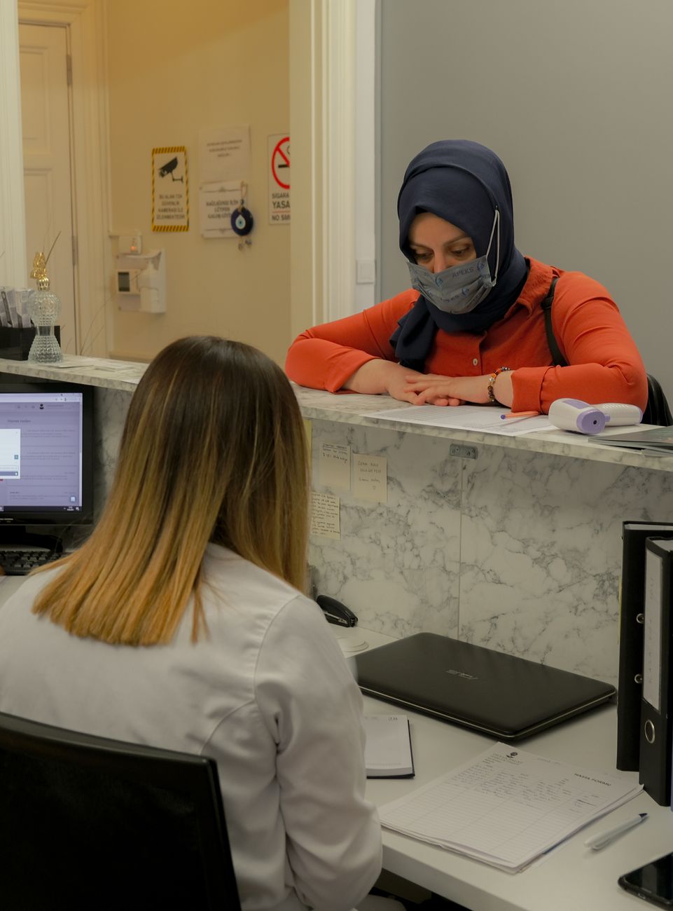 Patient at medical office reception discussing copay and payment