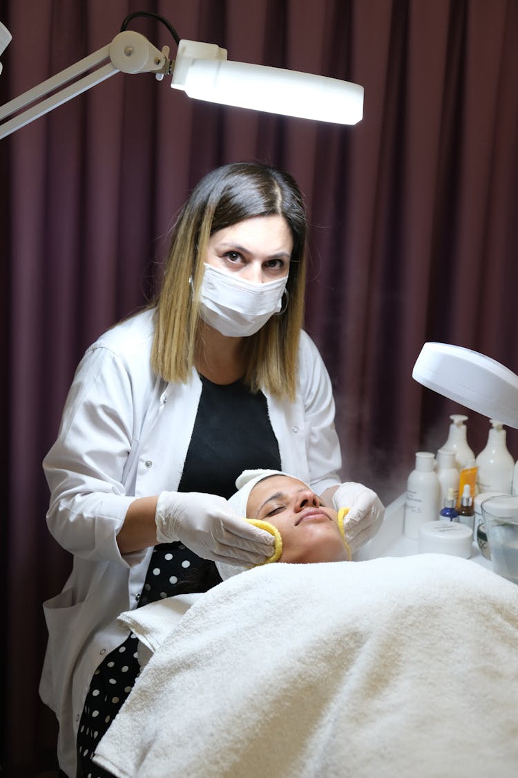 Woman In A Lab Coat Doing A Procedure On A Person