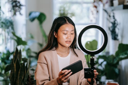 Woman holding Black Smartphone beside Ring Light 