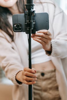 Close-up of a woman setting up a smartphone on a tripod for a vlogging session.