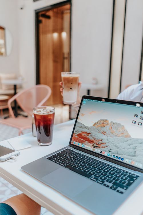 Free A cozy indoor workspace featuring a laptop, iced coffee, and stylish decor. Stock Photo