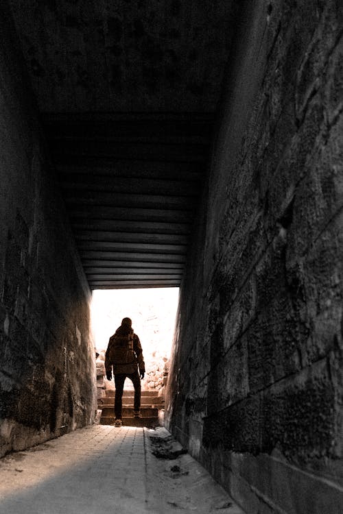 Man in Brown Jacket and Pants Near Gray Alley