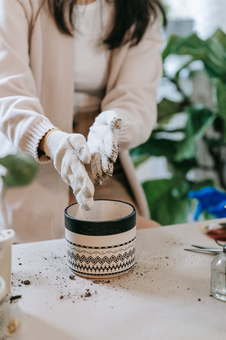 Person Wearing White Gloves Shaking Off The Remaining Soil