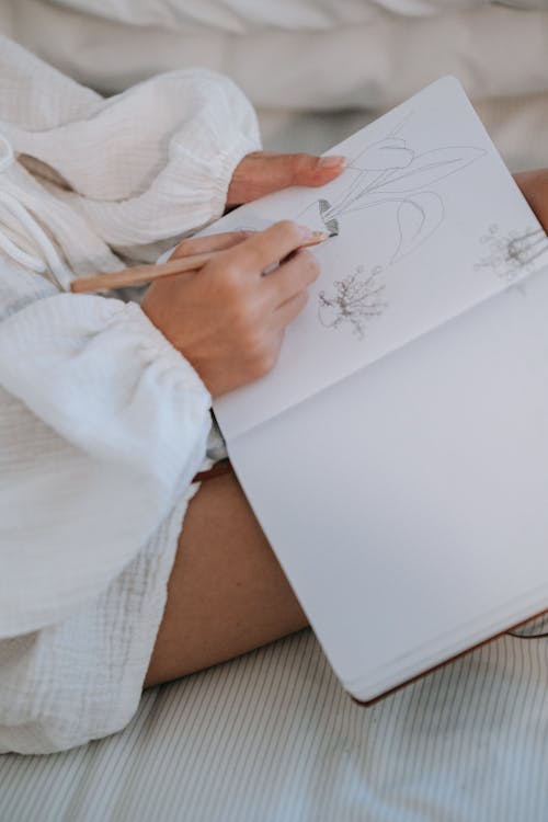 Person Drawing Plants on a White Notebook