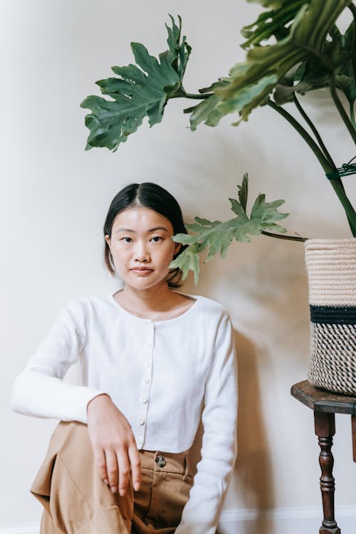 A Woman Sitting Beside a Potted Plant