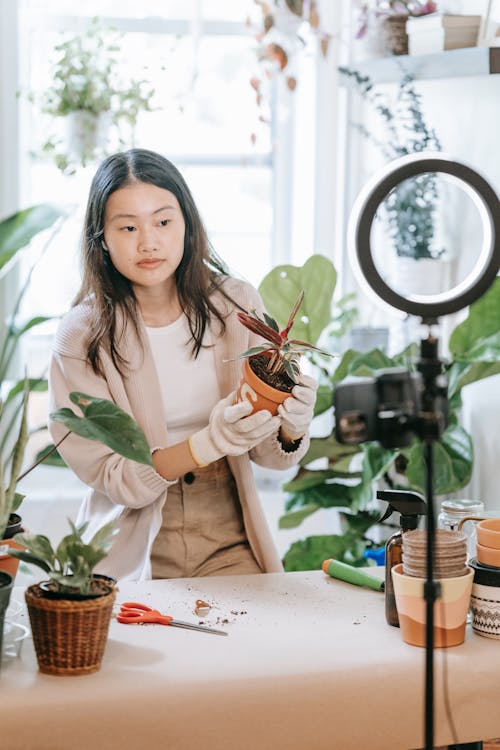 Woman Holding Her Potted Plant While Filming Herself 