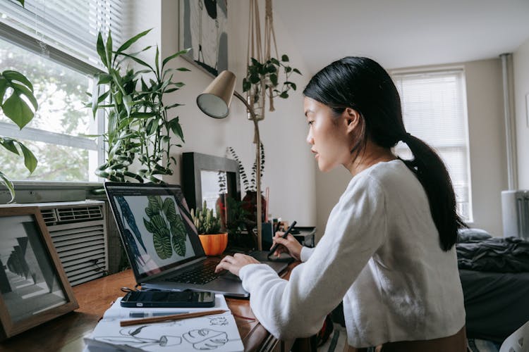 A Woman Looking At A Sketch On A Laptop