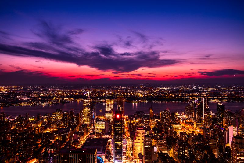 Aerial view of a glowing city beside a river at dusk