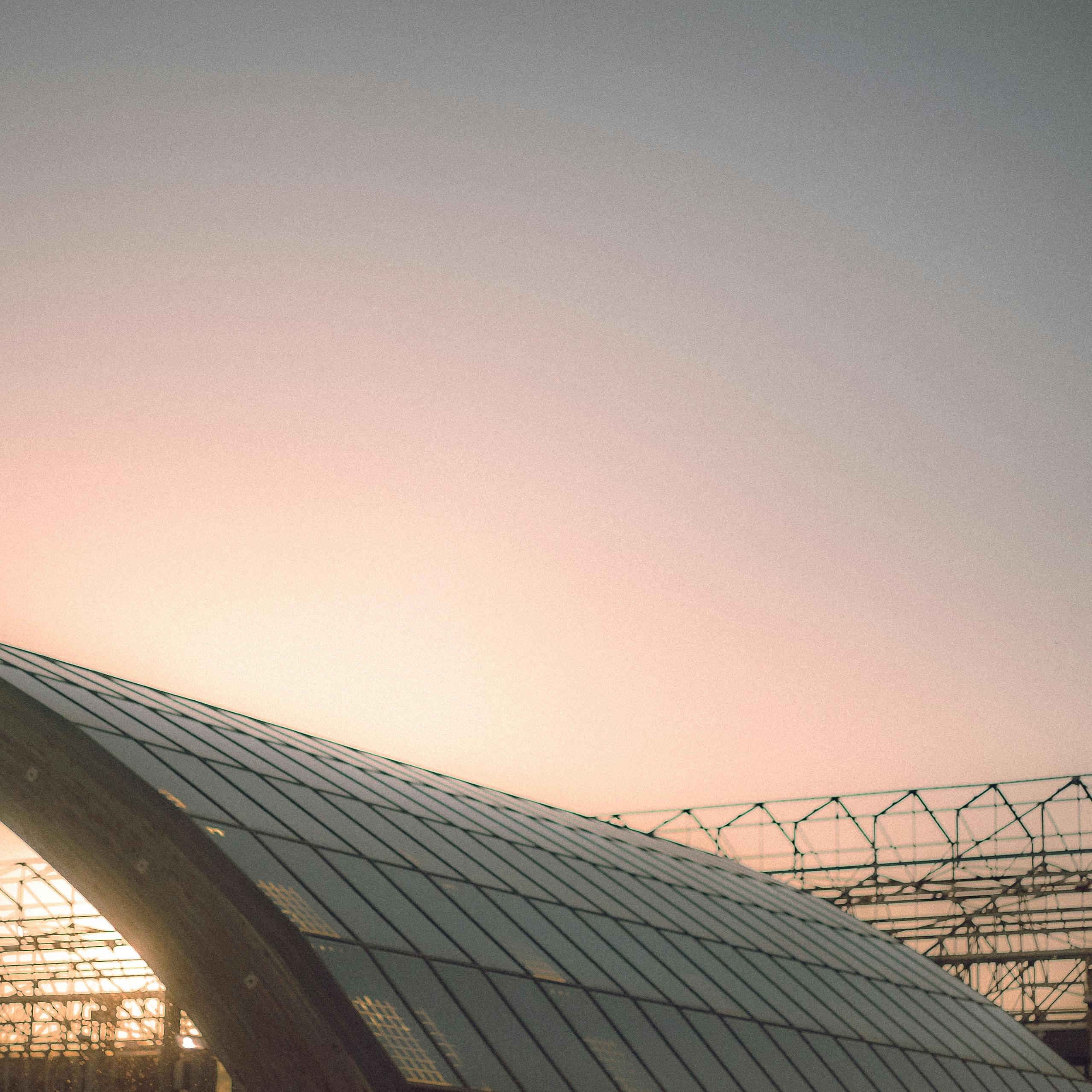 A stunning glass roof architecture silhouetted against a vibrant sunset sky, with ample copy space.