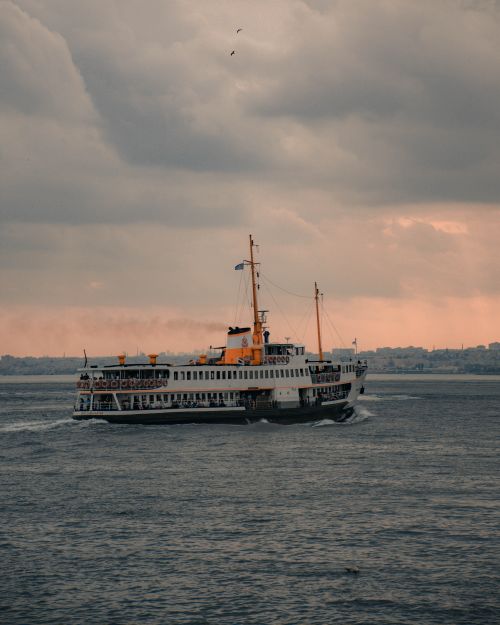 Free A ferry glides through a moody ocean under a cloudy sky, offering a dramatic travel scene. Stock Photo
