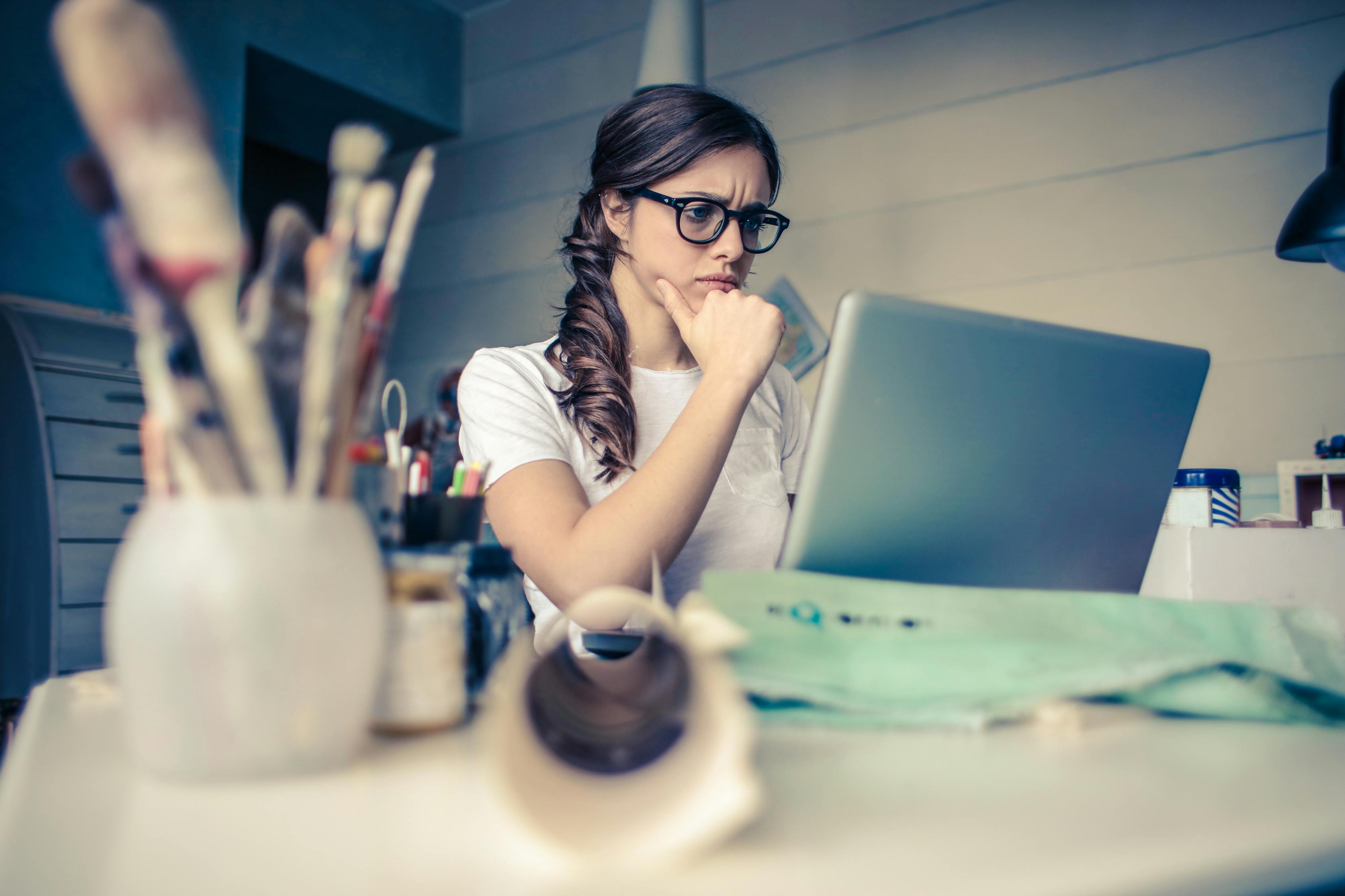 A woman thinking while on her computer.