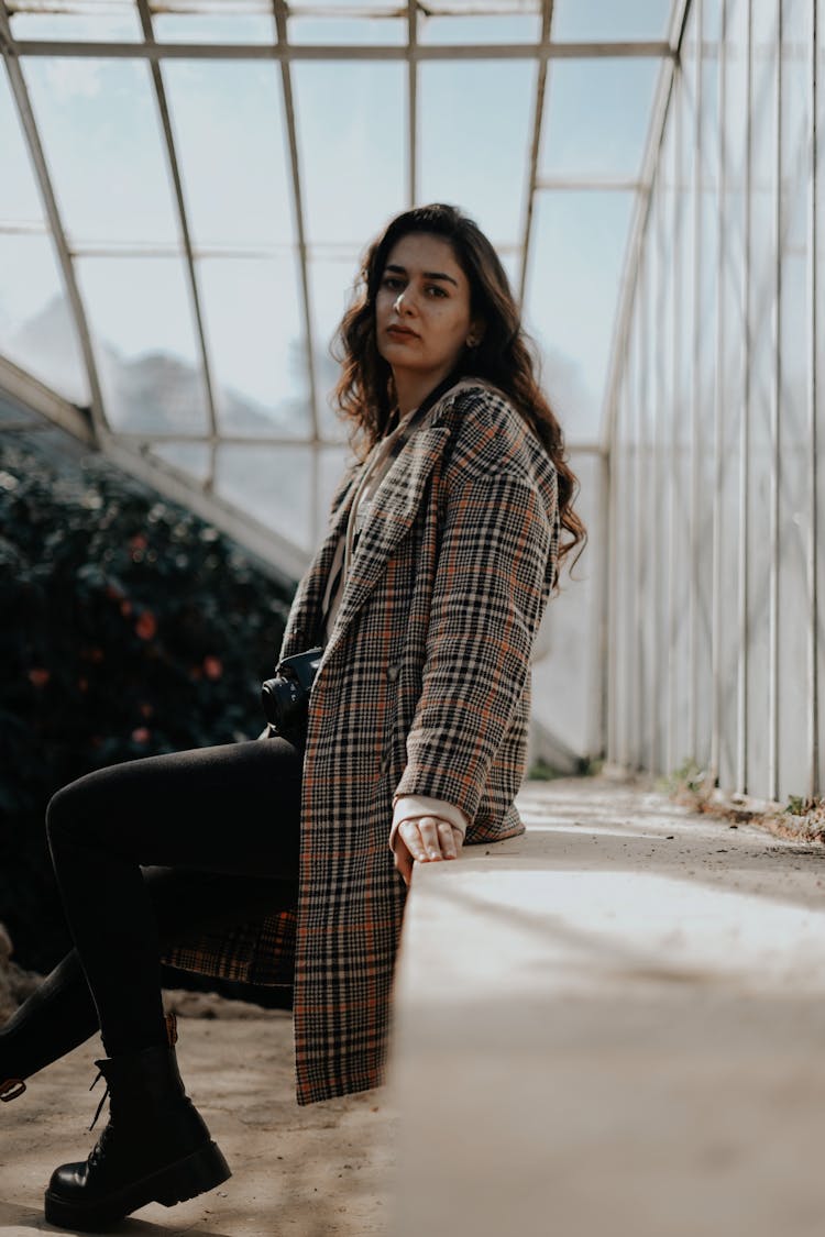 Woman Wearing Checked Coat Sitting Under Glass Ceiling